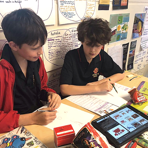 Two boys collaborate on a writing project.