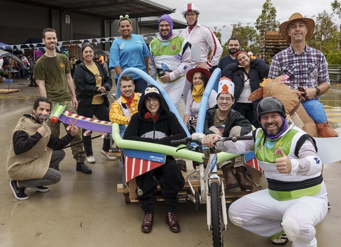 Bromic derby competitors dressed up in fun costumes, gathered around a creative kart design.