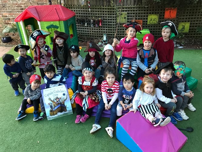 A group of preschool age children all gather in the playground of their learning centre to show off their pirate-y costumes, eye-patches and hats.